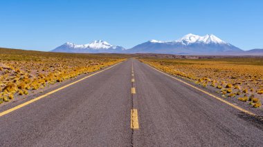 Karanlık bulutlu bir günde Şili 'deki Atacama Çölü' nü geçen sarı çizgilerle dolu uzun düz bir yol.. 