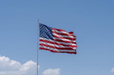 Arka planda mavi gökyüzü dalgalanan Birleşik Devletler bayrağı.