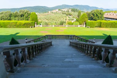 The stairs of Villa Medicea La Ferdinanda with the village Artimino in the background in Prato, Tuscany, Italy. Villa Medicea La Ferdinanda is one of the most famous of the Medicean villas of Tuscany. clipart