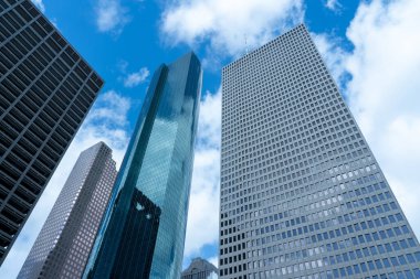 Houston, Teksas, ABD - 14 Nisan 2024: Arka planda mavi gökyüzü olan modern yüksek binalara bakmak.