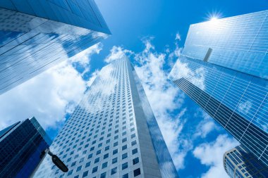 Looking Up modern high-rise office buildings with blue sky in the background.