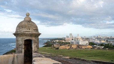 San Juan, Porto Riko 'da günbatımında şehrin arka planında bulunan Castillo San Cristobal Kalesi' nde taret. 1783 'te İspanya tarafından San Juan şehrine yapılan kara saldırılarına karşı korunmak için inşa edildi.