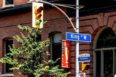 Toronto, Canada - July 31, 2019: Closeup of King St West street sign and traffic light in downtown Toronto Canada. King Street is a major east-west thoroughfare in Toronto. clipart