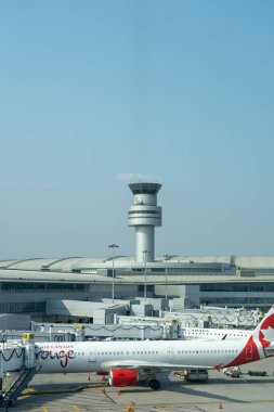 Mississauga, ON, Canada - September 13, 2024: An Air Canada rouge plane parked at Torontos Pearson International Airport with Air Traffic Control Tower in the background in Mississauga, ON, Canada. clipart