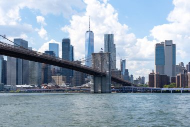 New York City, ABD - 19 Ağustos 2022: Brooklyn Köprüsü 'nün arka planında New York City, New York, ABD' deki binalar. Brooklyn Köprüsü bir hibrit kablo süspansiyon köprüsü..