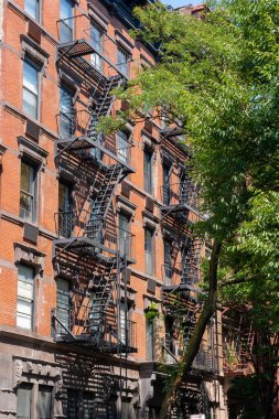 Yangın merdivenleri olan eski kırmızı tuğlalı bir apartman. New York City, ABD - 20 Ağustos 2022.