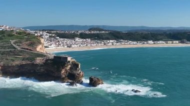Nazare, Portekiz 'deki deniz feneri. Dalgalar ve sörf için ünlü bir yer. Plaj ve Okyanus Dalgaları Arkaplanda. 4k