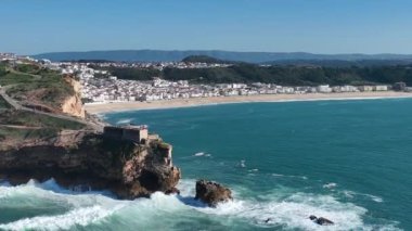 Nazare, Portekiz 'deki deniz feneri. Dalgalar ve sörf için ünlü bir yer. Plaj ve Okyanus Dalgaları Arkaplanda. 4k