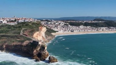 Nazare, Portekiz 'deki deniz feneri. Dalgalar ve sörf için ünlü bir yer. Plaj ve Okyanus Dalgaları Arkaplanda. 4k