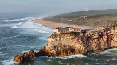 Nazare, Portekiz 'deki deniz feneri. Dalgalar ve sörf için ünlü bir yer. Plaj ve Okyanus Dalgaları Arkaplanda. 4k