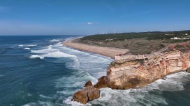 Nazare, Portekiz 'deki deniz feneri. Dalgalar ve sörf için ünlü bir yer. Plaj ve Okyanus Dalgaları Arkaplanda. 4k