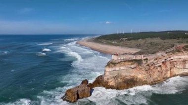 Nazare, Portekiz 'deki deniz feneri. Dalgalar ve sörf için ünlü bir yer. Plaj ve Okyanus Dalgaları Arkaplanda. 4k