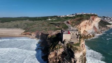 Nazare, Portekiz 'deki deniz feneri. Dalgalar ve sörf için ünlü bir yer. Plaj ve Okyanus Dalgaları Arkaplanda. 4k