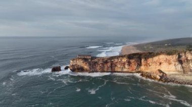 Nazare, Portekiz 'deki deniz feneri. Dalgalar ve sörf için ünlü bir yer. Plaj ve Okyanus Dalgaları Arkaplanda. 4k