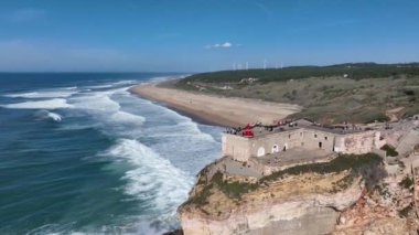 Nazare, Portekiz 'deki deniz feneri. Dalgalar ve sörf için ünlü bir yer. Plaj ve Okyanus Dalgaları Arkaplanda. 4k