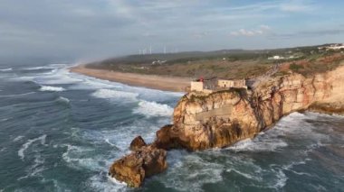 Nazare, Portekiz 'deki deniz feneri. Dalgalar ve sörf için ünlü bir yer. Plaj ve Okyanus Dalgaları Arkaplanda. 4k