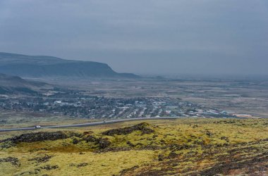 Dağ, Mavi Gökyüzü ve Arka planda Kasabası olan İzlanda manzarası.