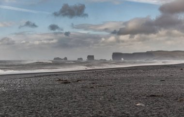 İzlanda 'daki Kara Kum Sahili Reynisfjara. Sudaki Kayalar. Okyanus Dalgaları. Rüzgarlı.