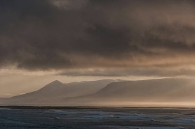 Arkaplanda Okyanus Suyu ve Bulutlu İzlanda manzarası