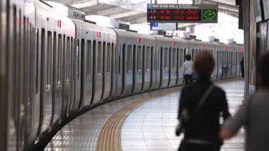 Metro Train Station Platform in Tokyo. Underground Metro Train During Rush Hour is Ready to Depart. People are Running to the Train. Conductor Checking Time. Asian commuters traveling.