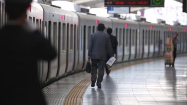 Metro Train Station Platform in Tokyo. Underground Metro Train During Rush Hour is Ready to Depart. People are Running to the Train. Conductor Checking Time. Asian commuters traveling.