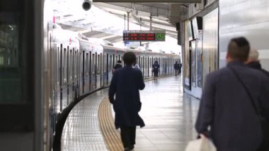 Metro Train Station Platform in Tokyo. Underground Metro Train During Rush Hour. People are Walking on Platform. Conductor Leaves the Train. Asian commuters traveling.