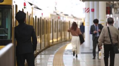 Metro Train Station Platform in Tokyo. Underground Metro Train Station During Rush Hour. Seibu Haijima Line Train and Condurctor Showing Signs. Asian commuters traveling.