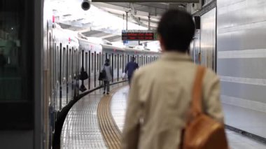 Metro Train Station Platform in Tokyo. Underground Metro Train During Rush Hour. People are Walking on Platform. Conductor Leaves the Train. Asian commuters traveling.