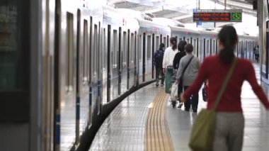 Metro Train Station Platform in Tokyo. Underground Metro Train During Rush Hour. People are Walking on Platform. Conductor Leaves the Train. Asian commuters traveling.