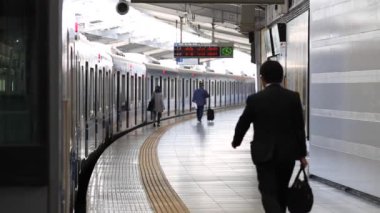 Metro Train Station Platform in Tokyo. Underground Metro Train During Rush Hour. People are Walking on Platform. Conductor Leaves the Train. Asian commuters traveling.
