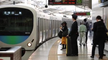 People are Walking on Platform in Metro Train Station Platform in Tokyo. Underground Metro Train During Rush Hour. Train is Approaching. Asian commuters traveling.