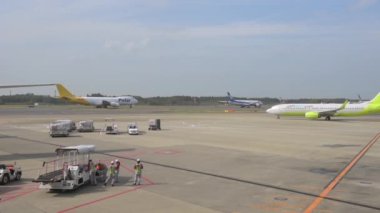 Tokyo International Narita Airport and Ground Service is Working in Background. Jin Air, ANA and Polar DHL Airplanes are Taxing to Take Off. Bright Sunny Day