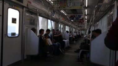 Tokyo Metro. Full Underground Metro Train During Rush Hour In Tokyo. People Are Sitting and Reading. Japanese people commuting on local train. Tourists on crowded train. Asian commuters traveling