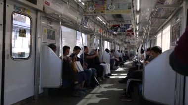 Tokyo Metro. Full Underground Metro Train During Rush Hour In Tokyo. People Are Sitting and Reading. Japanese people commuting on local train. Tourists on crowded train. Asian commuters traveling