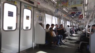 Tokyo Metro. Full Underground Metro Train During Rush Hour In Tokyo. People Are Sitting and Reading. Japanese people commuting on local train. Tourists on crowded train. Asian commuters traveling