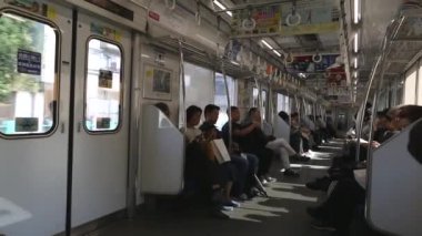 Tokyo Metro. Full Underground Metro Train During Rush Hour In Tokyo. People Are Sitting and Reading. Japanese people commuting on local train. Tourists on crowded train. Asian commuters traveling