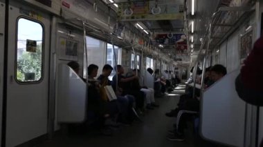 Tokyo Metro. Full Underground Metro Train During Rush Hour In Tokyo. People Are Sitting and Reading. Japanese people commuting on local train. Tourists on crowded train. Asian commuters traveling