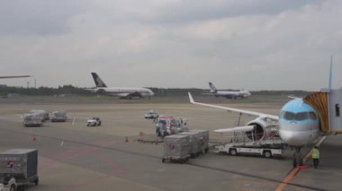Korean Airlines airplane Airbus a220 arrived to Tokyo International Narita Airport. Ground Service is Working in Background. Singapore and Nippon Cargo Airlines Airplanes Are Taxing to Take Off.