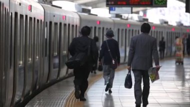 Metro Train Station Platform in Tokyo. Underground Metro Train During Rush Hour is Ready to Depart. People are Running to the Train. Conductor Checking Time. Asian commuters traveling.