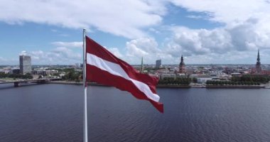 Latvian Flag Waving. Dauguva River in Background. Riga