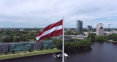 Latvian Flag Waving. Dauguva River in Background. Riga