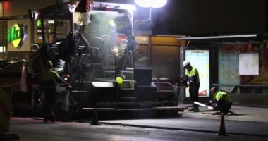 Road repair at night. Asphalt paver applying asphalt on the street. Construction of a new road. A layer of freshly laid asphalt in the city. Vilnius city, Lithuania