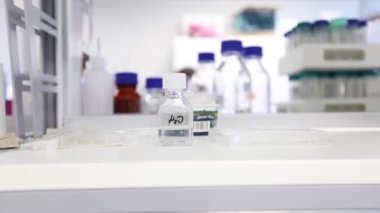 Water Bottle H2O in Laboratory. Sterile Conditions. Chemistry and Laboratory Glassware in Background