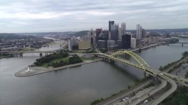 Pittsburgh Cityscape in cloudy day, Pennsylvania. Daytime with business district and river with three bridges in background. Fort Pitt Bridge in foreground