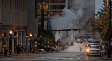 Baltimore, Maryland - October 03, 2019: Traffic in Baltimore, Maryland. USA. Hot Water Steam in Background. Downtown Street