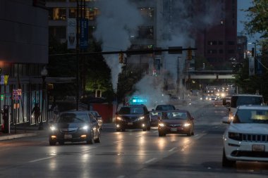 Baltimore, Maryland - October 03, 2019: Traffic in Baltimore, Maryland. USA. Hot Water Steam in Background. Downtown Street