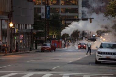 Baltimore, Maryland - October 03, 2019: Traffic in Baltimore, Maryland. USA. Hot Water Steam in Background. Downtown Street