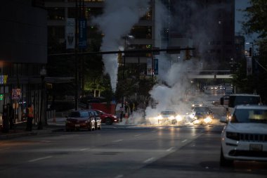 Baltimore, Maryland - October 03, 2019: Traffic in Baltimore, Maryland. USA. Hot Water Steam in Background. Downtown Street