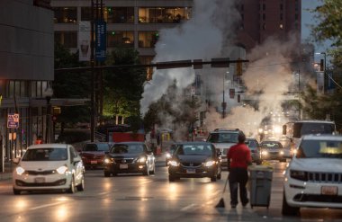 Baltimore, Maryland - October 03, 2019: Traffic in Baltimore, Maryland. USA. Hot Water Steam in Background. Downtown Street