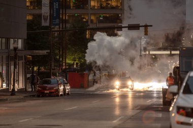 Baltimore, Maryland - October 03, 2019: Traffic in Baltimore, Maryland. USA. Hot Water Steam in Background. Downtown Street